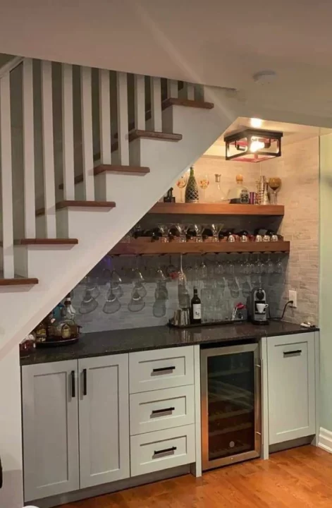 صورة لتصميم مطبخ تحت الدرج او السلم الداخلي. تحتوي الصورة على وحدات تخزين وارفف ورخام مطبخ.